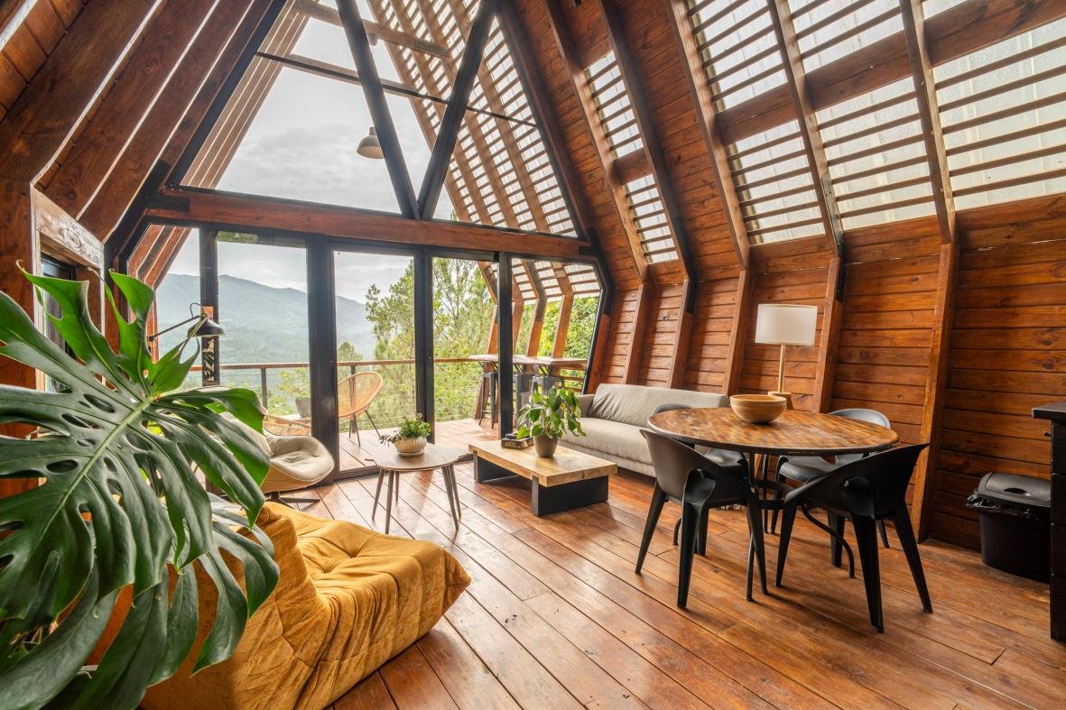 A-Frame living and dining area with timber walls and full-height glazing